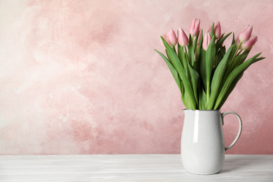 Photo of Beautiful pink spring tulips in vase on white wooden table. Space for text