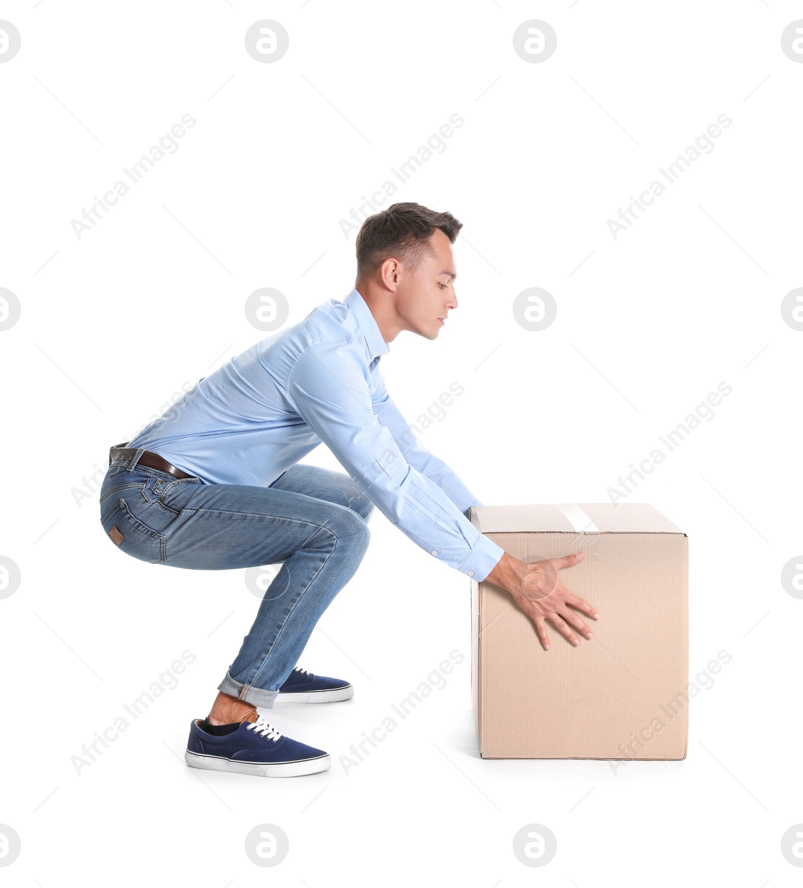 Photo of Full length portrait of young man lifting heavy cardboard box on white background. Posture concept