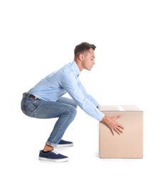 Photo of Full length portrait of young man lifting heavy cardboard box on white background. Posture concept