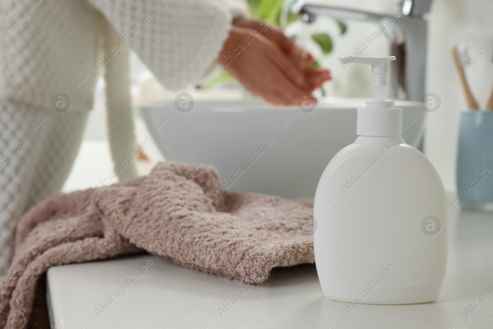 Photo of Woman washing hands with liquid soap in bathroom, focus on dispenser. Space for text