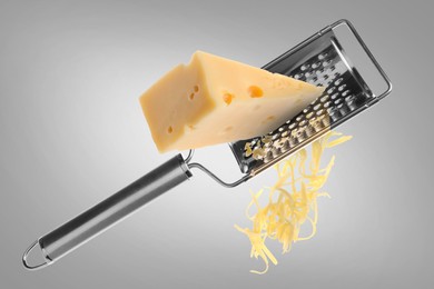 Image of Grating cheese with hand grater on grey background