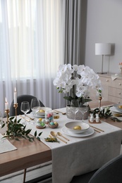 Photo of Beautiful Easter table setting with orchid flowers indoors