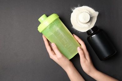 Woman with bottle of water, protein powder and space for text on black background, top view. Preparing shake