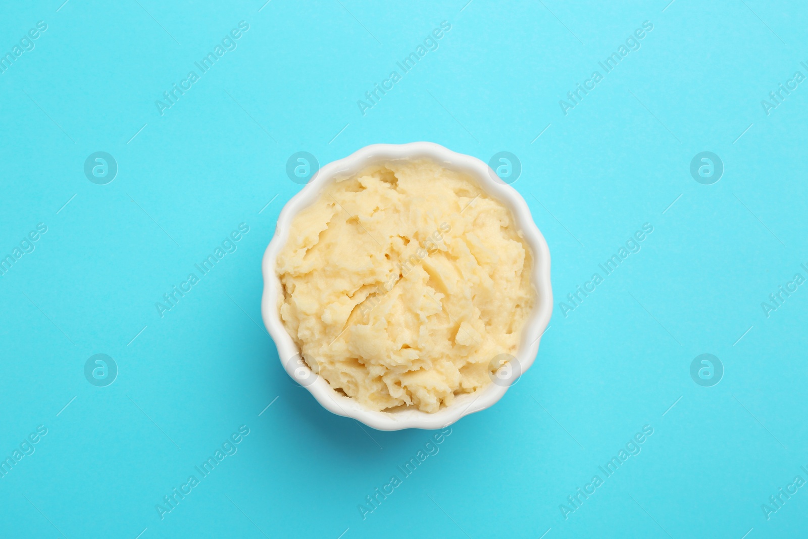 Photo of Bowl with tasty mashed potatoes on color background, top view