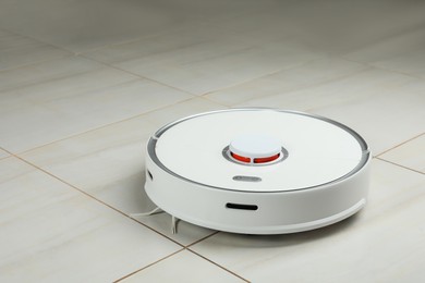 Photo of Robotic vacuum cleaner on white tiled floor indoors