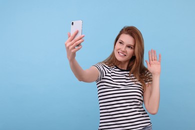 Photo of Beautiful woman taking selfie on light blue background