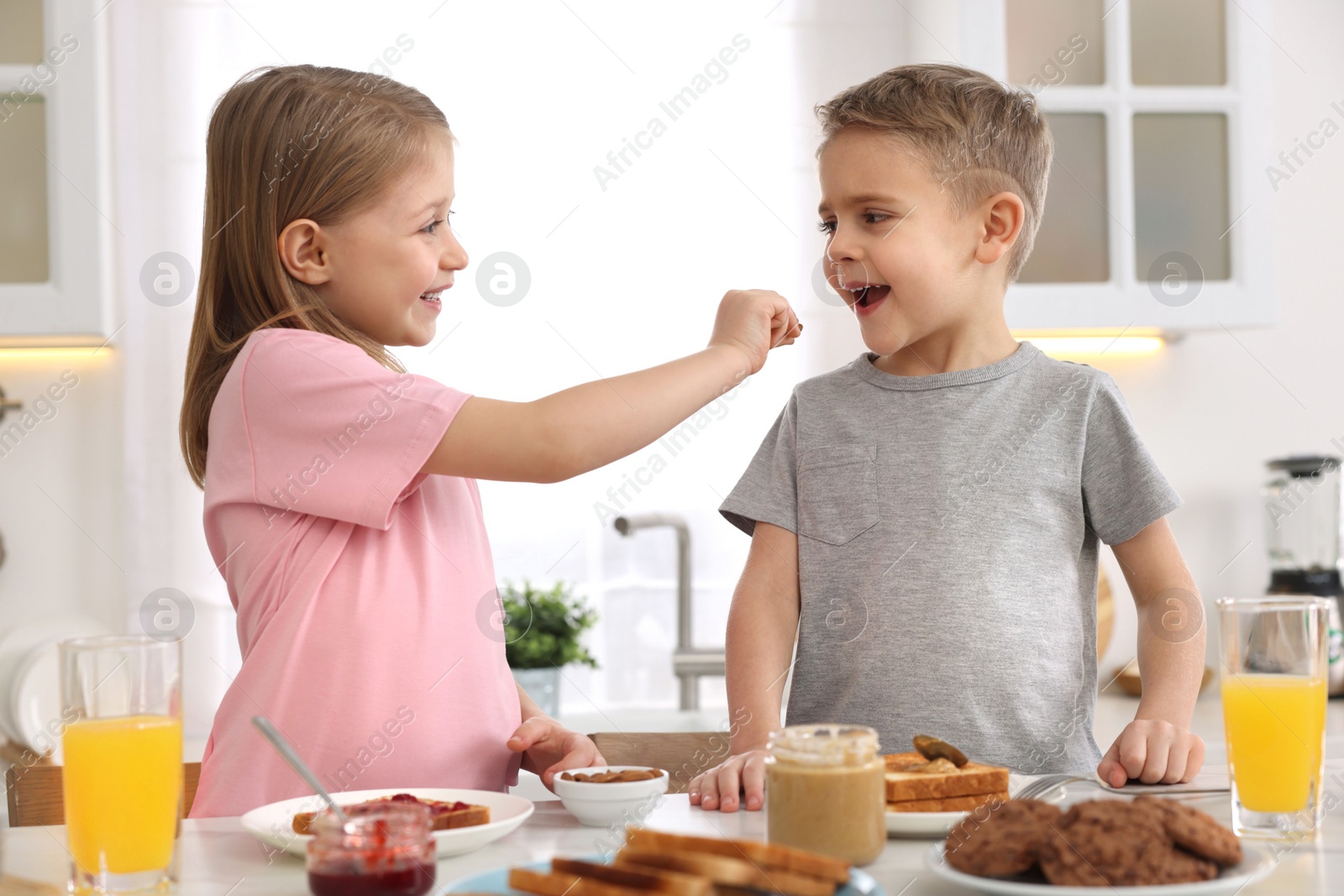 Photo of Little children having fun during breakfast at table in kitchen