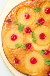 Photo of Tasty pineapple cake with cherries and mint on white table, top view