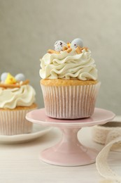 Photo of Tasty Easter cupcakes with vanilla cream on light wooden table