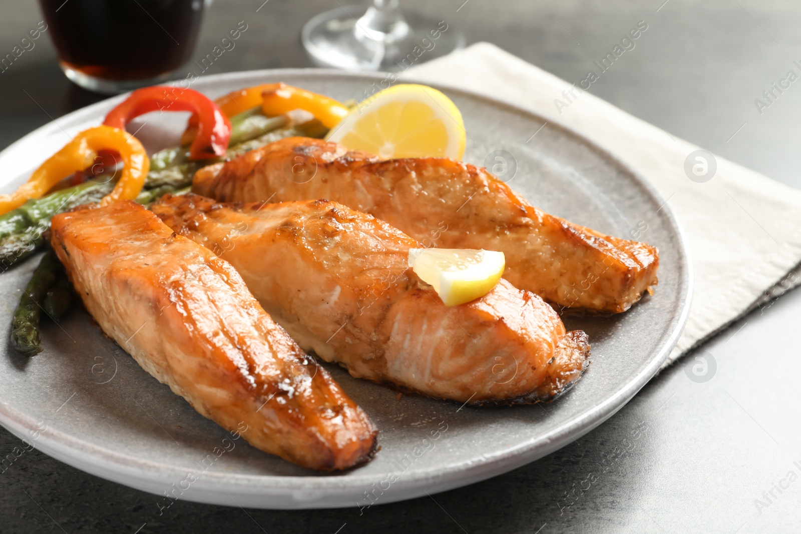 Photo of Tasty cooked salmon with vegetables on plate, closeup