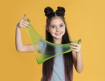 Photo of Little girl with slime on yellow background