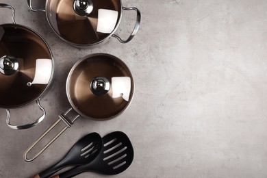 New cookware set and kitchen utensils on light grey table, flat lay. Space for text