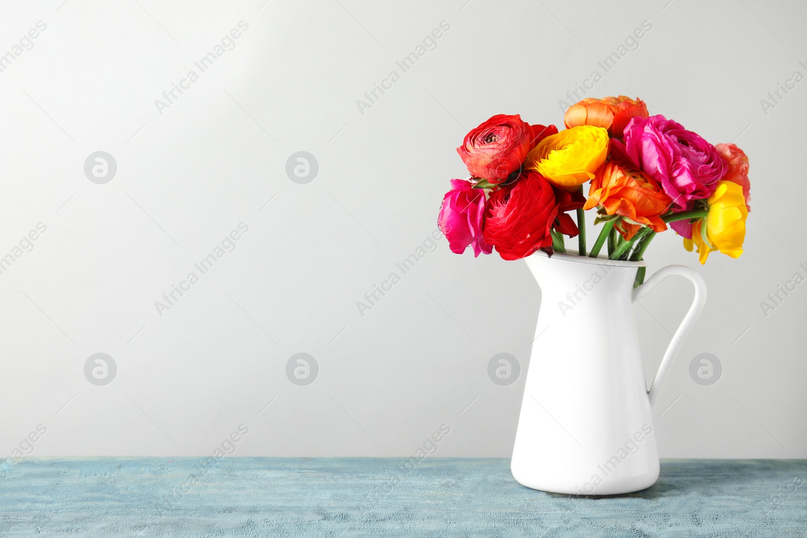 Photo of Vase with beautiful spring ranunculus flowers on table, space for text