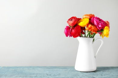 Photo of Vase with beautiful spring ranunculus flowers on table, space for text