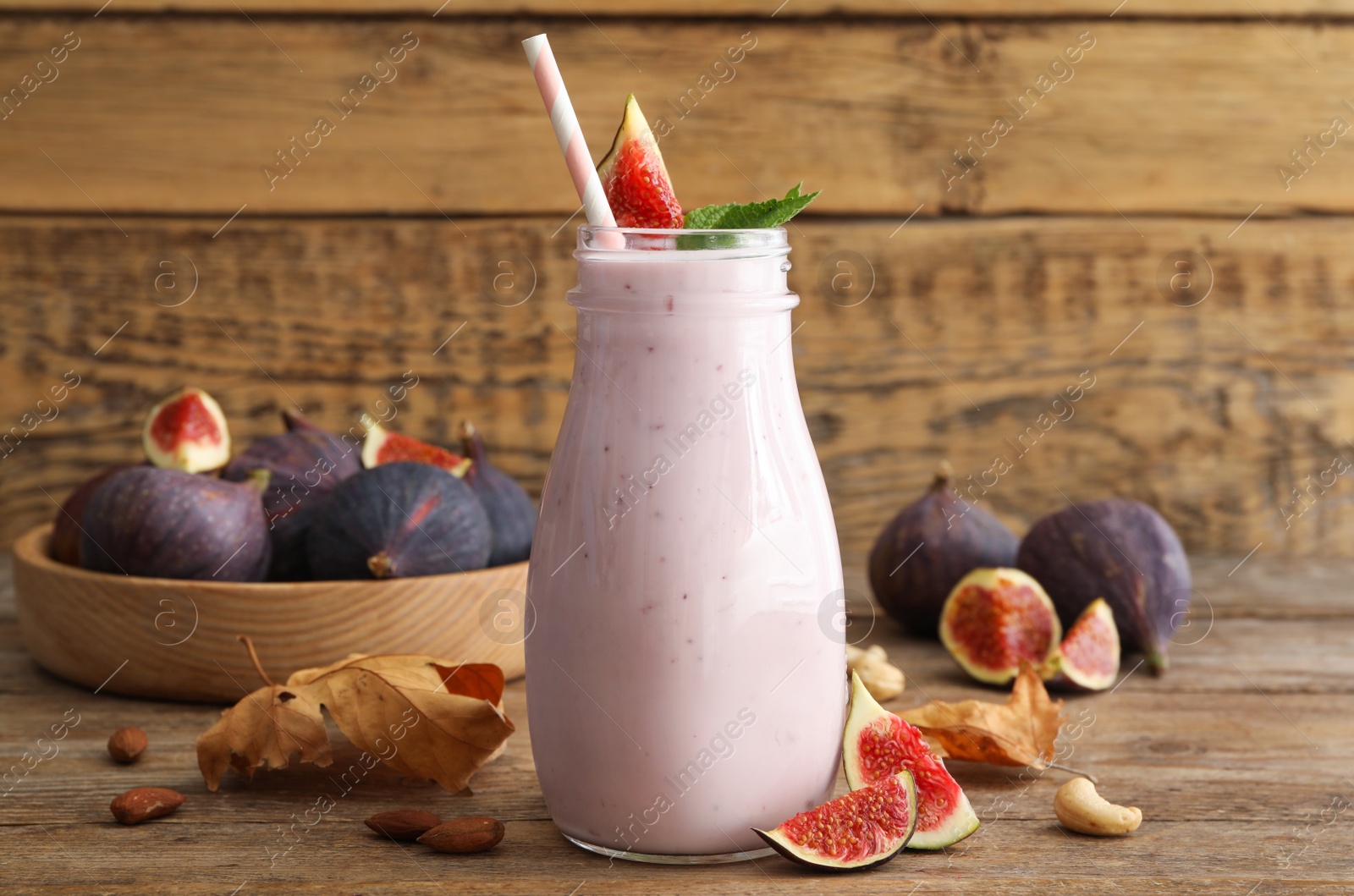 Photo of Delicious fig smoothie in glass bottle on wooden table