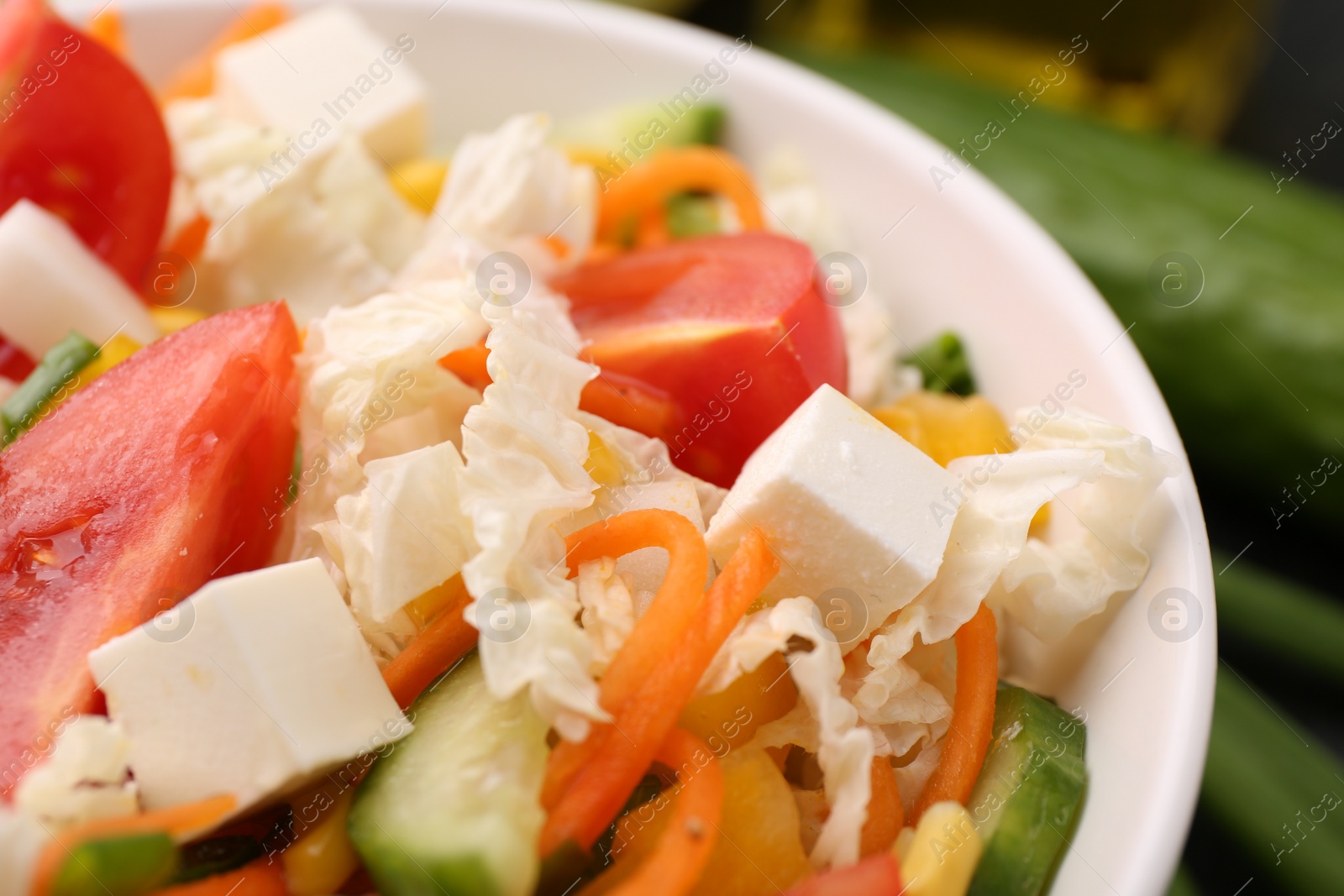 Photo of Tasty salad with Chinese cabbage, carrot, cheese, cucumber and tomato on table, closeup