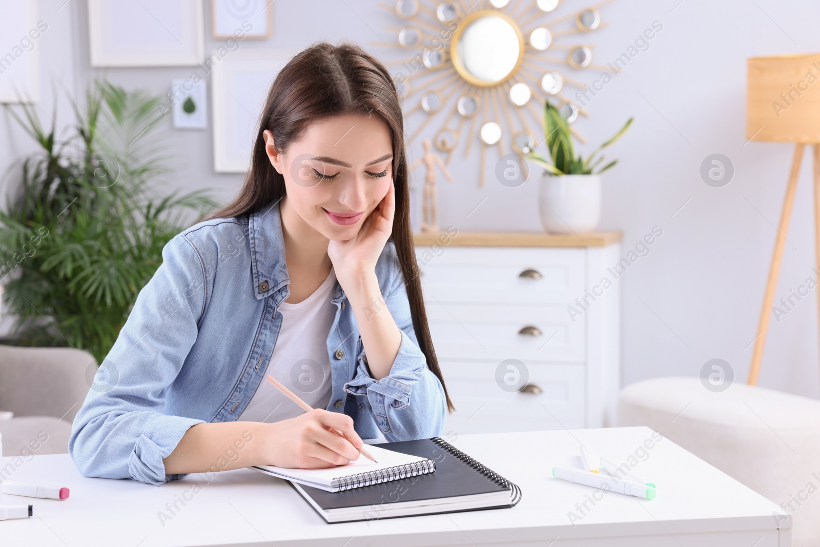 Photo of Young woman drawing in sketchbook at home, space for text