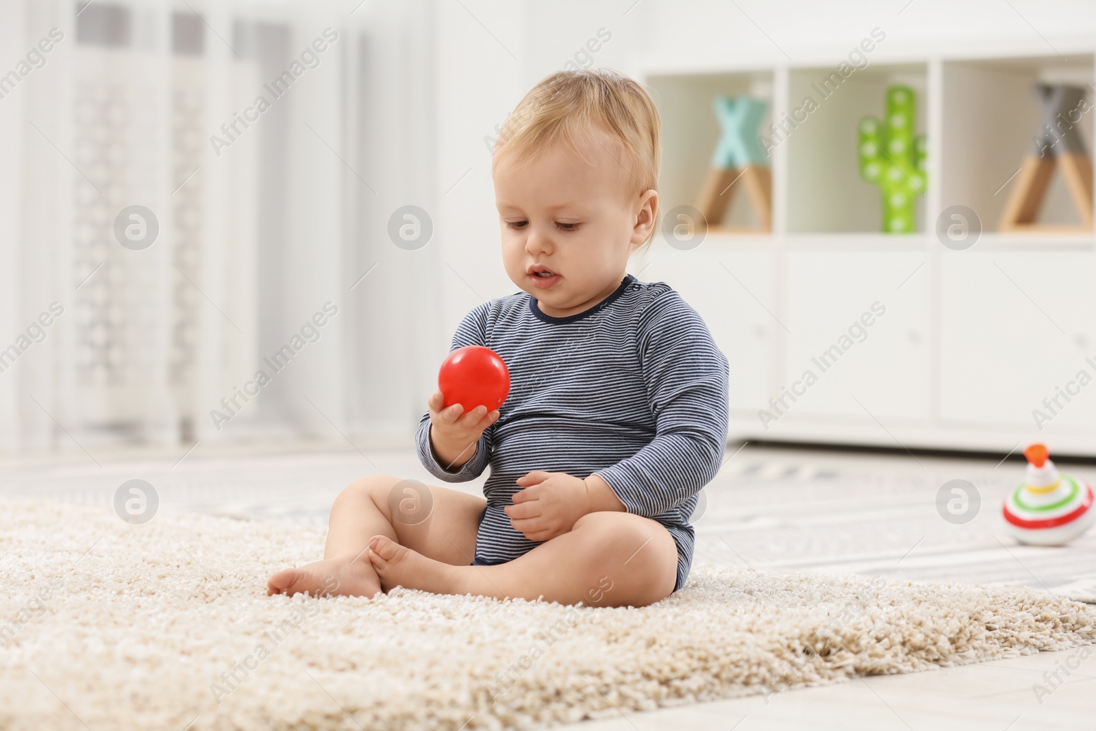 Photo of Children toys. Cute little boy playing with red ball on rug at home