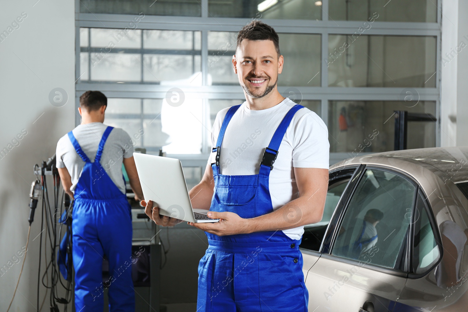 Photo of Mechanic with laptop doing car diagnostic at automobile repair shop