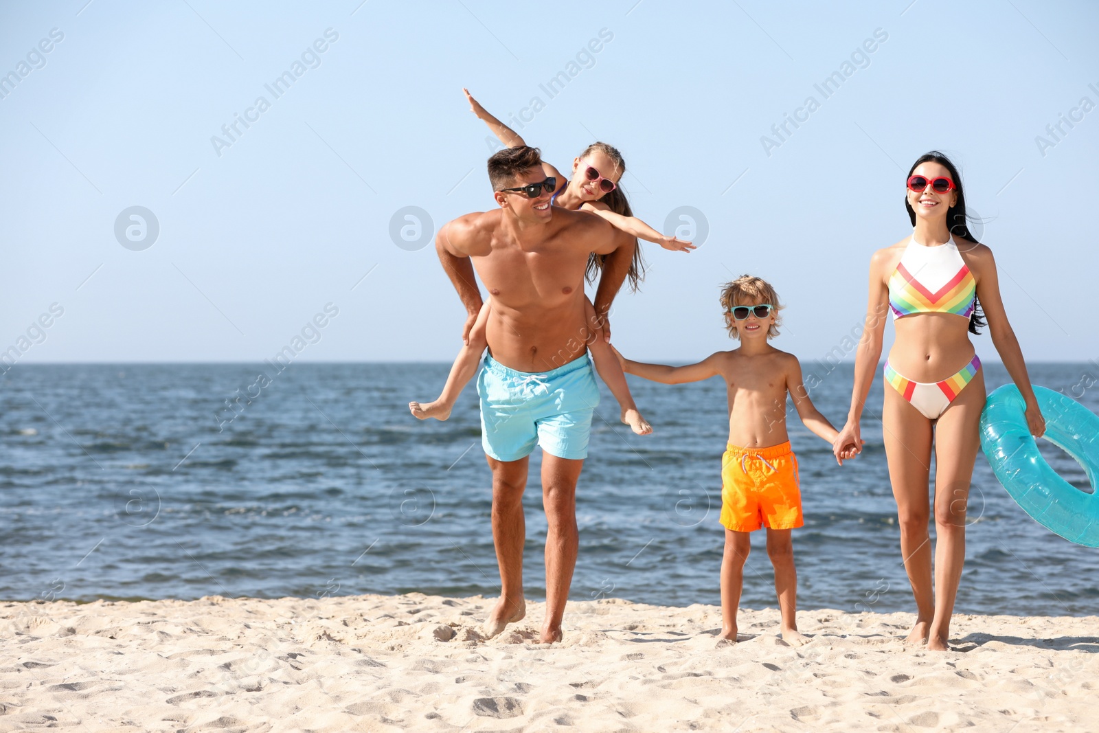 Photo of Happy family with inflatable ring on sandy beach near sea. Summer holidays