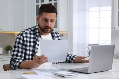 Photo of Man doing taxes at table in kitchen