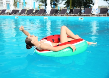 Photo of Beautiful young woman wearing bikini on inflatable ring in swimming pool