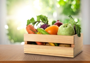 Wooden crate with fresh vegetables on table in kitchen