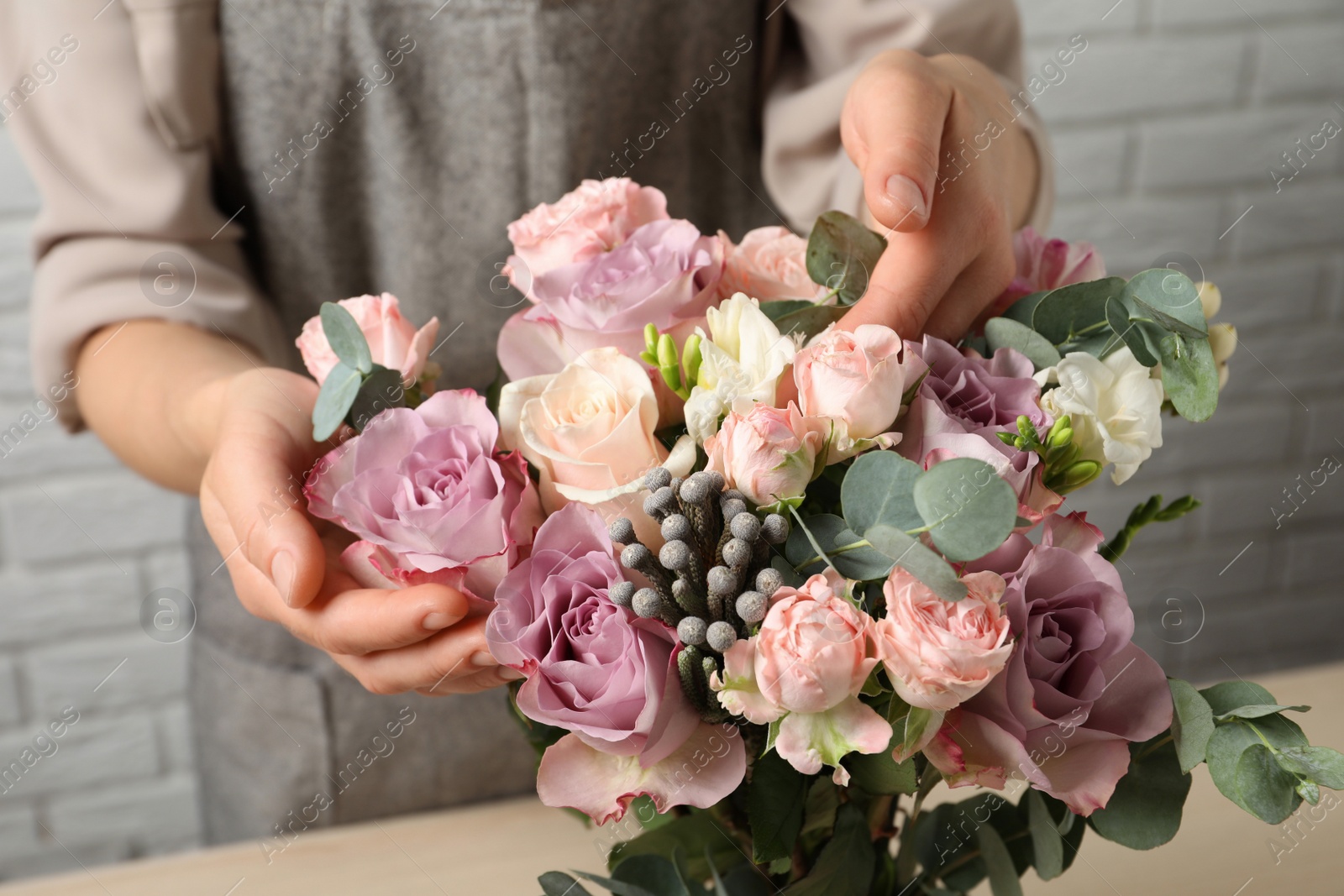 Photo of Florist creating beautiful bouquet at table indoors, closeup