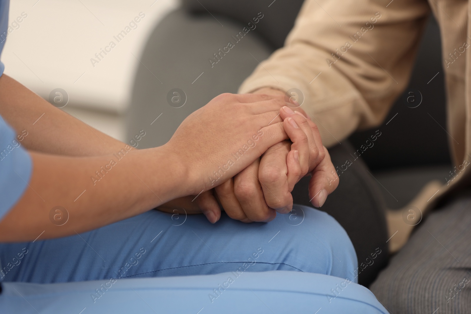 Photo of Nurse supporting elderly patient indoors, closeup view