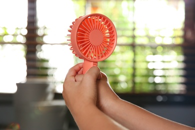 Photo of Little child with portable fan at home, closeup. Summer heat