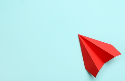 Photo of Red paper plane on light blue background, top view. Space for text