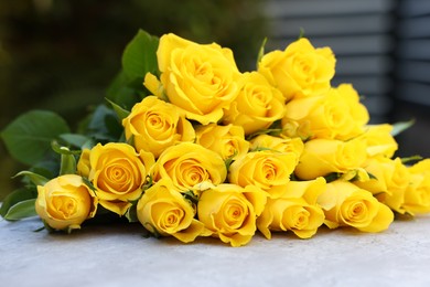 Beautiful bouquet of yellow roses on light table outdoors, closeup