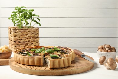 Delicious quiche with mushrooms and basil on white wooden table