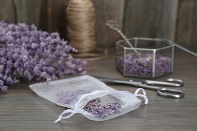 Photo of Scented sachet with dried lavender flowers on wooden table