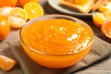 Photo of Delicious tangerine jam on wooden table, closeup