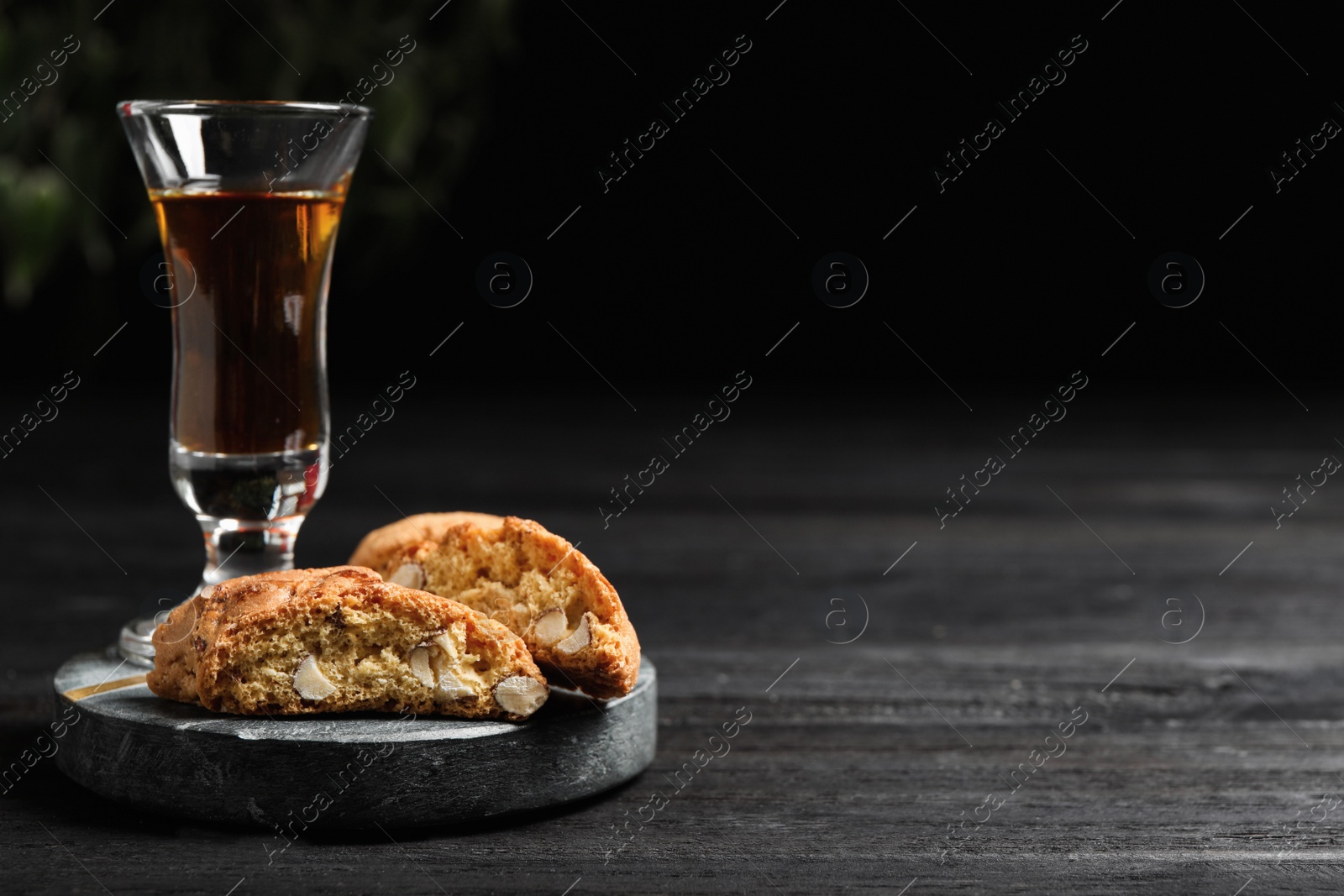 Photo of Tasty cantucci and glass of liqueur on wooden table, space for text. Traditional Italian almond biscuits
