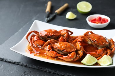Delicious boiled crabs with sauce and lime on black textured table