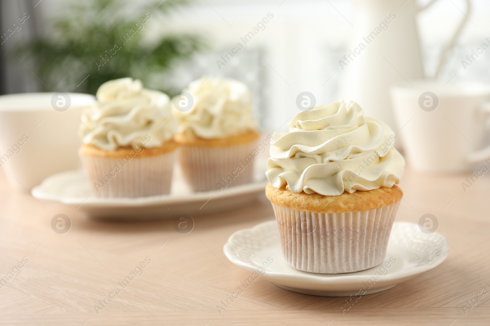 Photo of Tasty cupcakes with vanilla cream on light wooden table, closeup