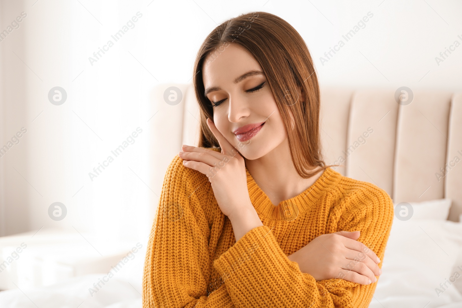 Photo of Young woman wearing warm sweater on bed at home. Winter season