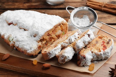Photo of Traditional Christmas Stollen with icing sugar on wooden board, closeup