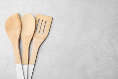 Photo of Set of wooden cooking utensils on light grey table, flat lay. Space for text