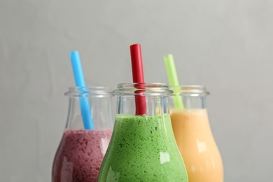 Bottles with healthy detox smoothies on grey background, closeup