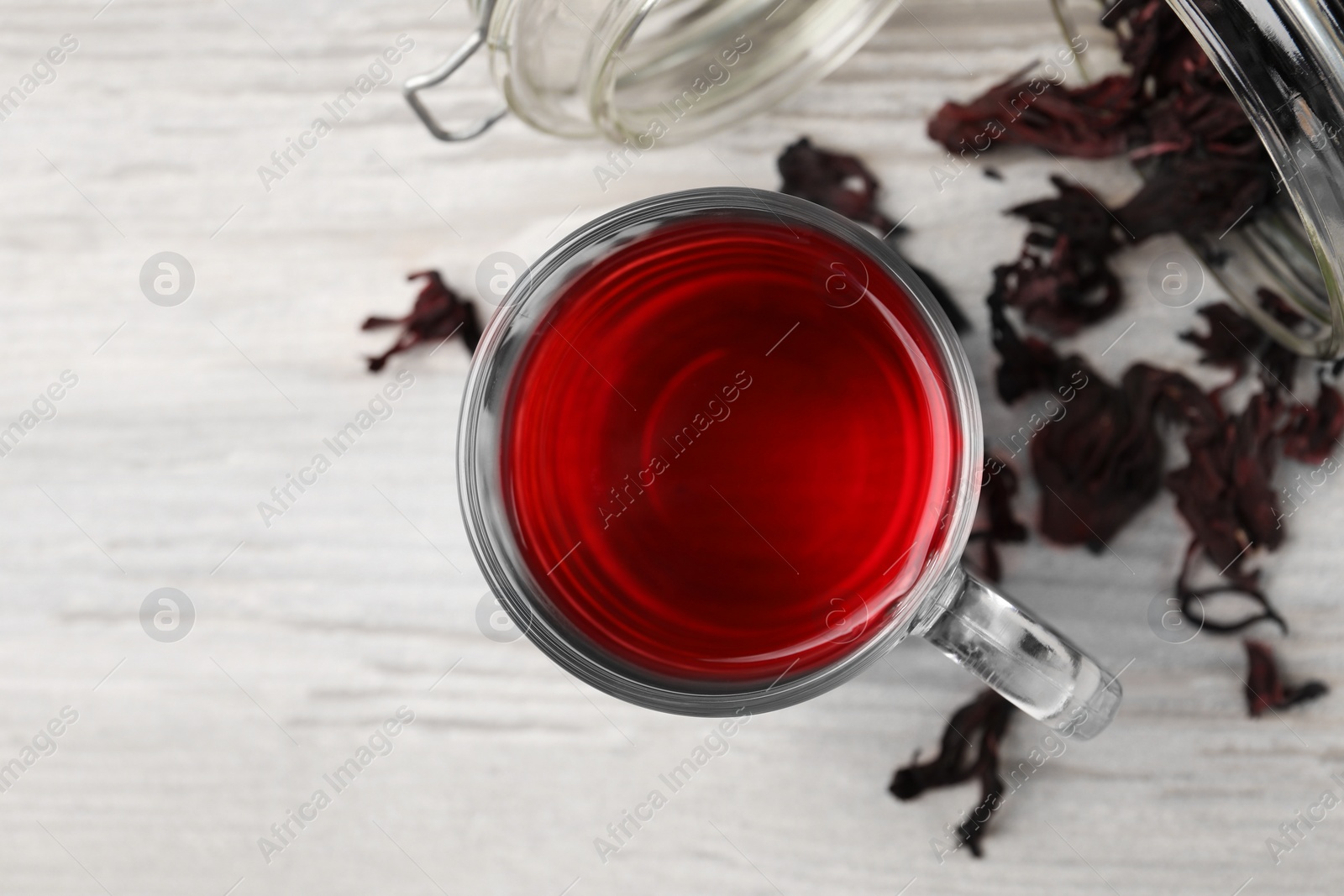 Photo of Delicious hibiscus tea and dry flowers on white wooden table, flat lay