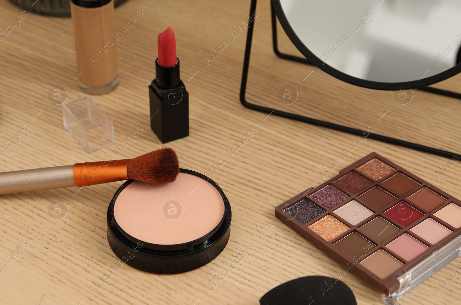 Photo of Mirror and cosmetic products on wooden dressing table, closeup