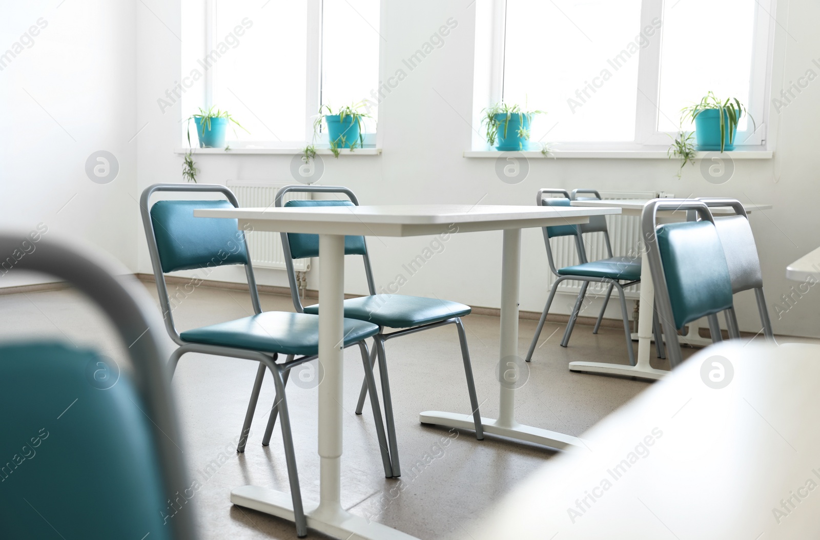 Photo of Empty school classroom with desks, windows and chairs