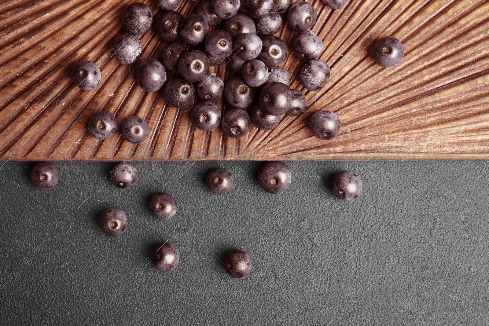 Photo of Fresh acai berries on wooden board, top view