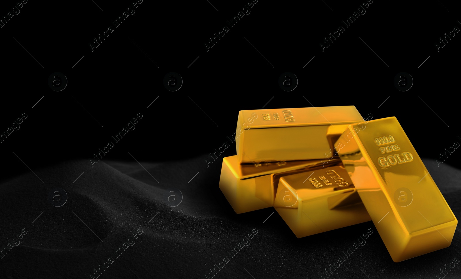 Image of Shiny gold bars on black sand, space for text