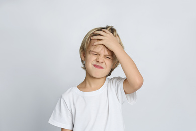 Unhappy little boy on light grey background