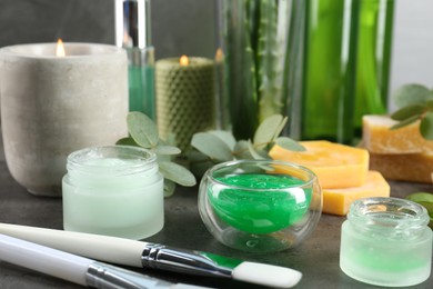 Photo of Homemade cosmetic products, fresh ingredients and brushes on black table