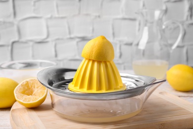 Photo of Citrus juicer and squeezed lemon on wooden board